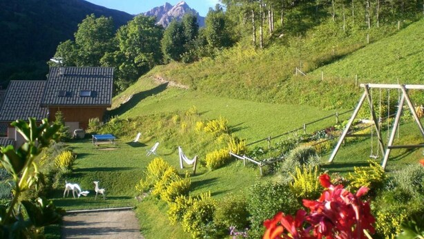 A rural house with a sloped roof, surrounded by a garden with various plants and a swing set. - 1st floor, terrace, ski locker, 30m², Valloire (Valloire)