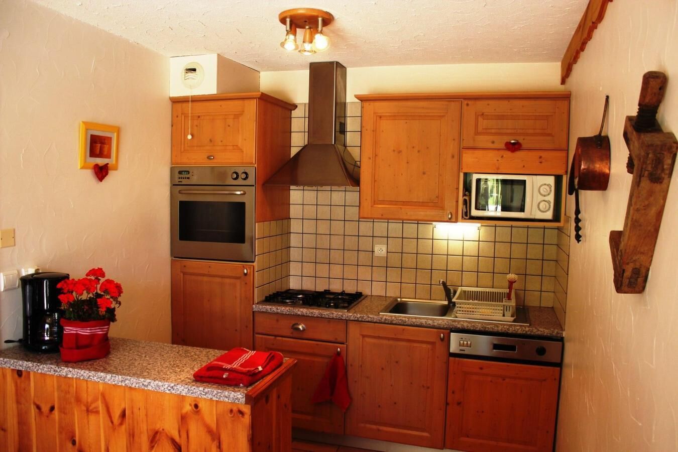 A compact kitchen with wooden cabinets, a built-in oven, a microwave, and a gas stove.