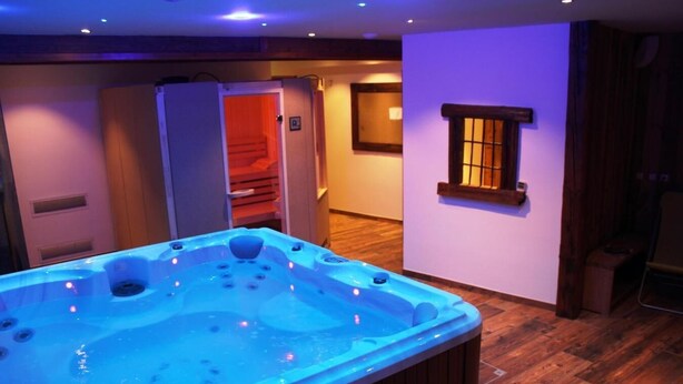 Quarto com hidromassagem, piso de madeira, janela com vista e porta que dá para outro cômodo.