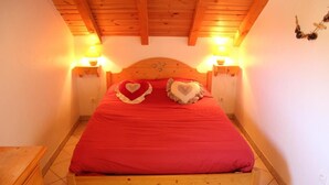 A wooden bed with a red bedspread and heart-shaped pillows, flanked by two wall-mounted lamps. - 2nd floor, balcony, ski locker, 92m², Valloire (Valloire)