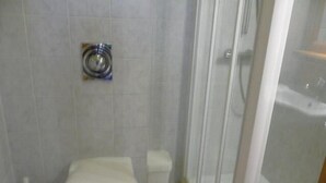 Ein Badezimmer mit Toilette, Duschkabine und Toilettenbürste.