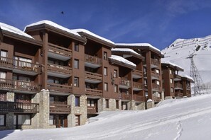 A multi-story hotel with balconies and stone pillars, surrounded by snow and a ski slope. - Ski-in/ski-out & foot of the slopes, view ski slopes, tv, 18m², La Plagne (La Plagne)