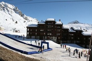 A ski resort with a ski lift, a large building with multiple floors, and a snowy mountain backdrop. - Ski-in/ski-out & foot of the slopes, view ski slopes, tv, 18m², La Plagne (La Plagne)