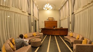 A spacious lobby with a reception desk, two sofas, and a chandelier. - Maple Leaf Hotel (Masaka)
