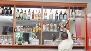 A bar area with shelves of various liquor bottles and glasses. - Maple Leaf Hotel (Masaka)