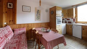 Una cocina acogedora de estilo rústico con armarios de madera, una mesa de comedor con mantel a cuadros y un banco de madera.