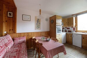 Eine gemütliche Küchenzeile im Blockhausstil mit Holzschränken, einem Esstisch mit kariertem Tischläufer und einer hölzernen Bank.