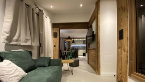 Ein modernes Wohnzimmer mit einem grünen Sofa, einem kleinen Tisch und einer Küche im Hintergrund.