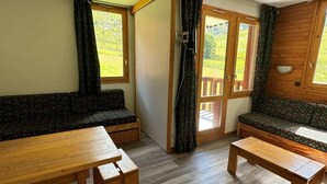 Et rum med to træbænke, et træbord og et vindue med gardiner.