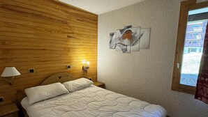 Ein Schlafzimmer mit Holzwänden, einem Bett, Nachttischlampen und einem an der Wand hängenden Bild.