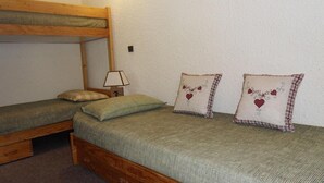 Ein Studentenwohnheimzimmer mit zwei Einzelbetten, einem Schlafkoje und einem Nachttisch mit Lampe, sowie dekorativen Kissen.