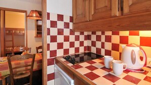 A compact kitchen with a checkered tile backsplash, wooden cabinets, a gas stove, and a kettle on the counter. - 50m from resort center, Ground floor, tv, ski locker, 28m², La Plagne (La Plagne)