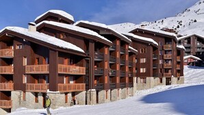 A row of wooden ski lodges with balconies, set against a snowy mountain backdrop. - 50m from resort center, Ground floor, tv, ski locker, 28m², La Plagne (La Plagne)
