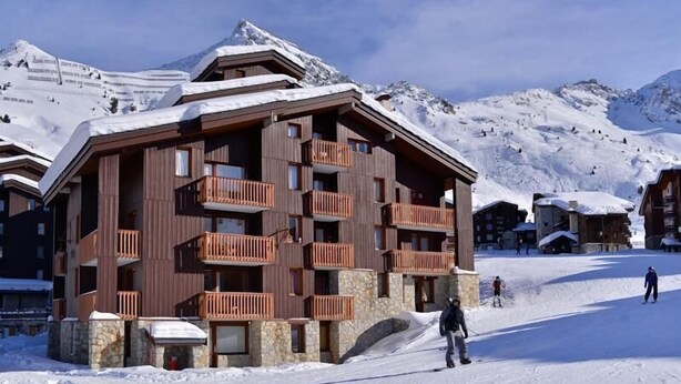 A multi-story wooden building with balconies, surrounded by snow-covered mountains. - 50m from resort center, Ground floor, tv, ski locker, 28m², La Plagne (La Plagne)
