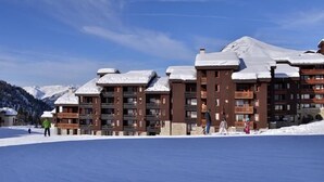 Un centro de esquí con edificios de varios pisos, techos cubiertos de nieve y un cielo azul despejado.