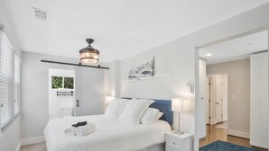 Une chambre à coucher avec un lit, une table de chevet et un ventilateur de plafond.