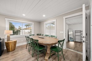 Un coin repas avec une table ronde en bois, des chaises vertes et une lampe.