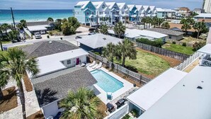 A coastal residential area with a row of blue houses, a swimming pool, and a view of the ocean. - Fam & Pet Friendly, PVT Heated Pool Steps 2 Beach (Panama City Beach)