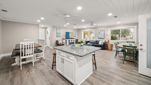 A spacious kitchen with a central island, white cabinetry, and a dining area with green chairs. - Fam & Pet Friendly, PVT Heated Pool Steps 2 Beach (Panama City Beach)