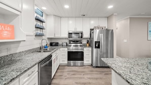 A modern kitchen with white cabinetry, granite countertops, stainless steel appliances, and a built-in oven. - Fam & Pet Friendly, PVT Heated Pool Steps 2 Beach (Panama City Beach)