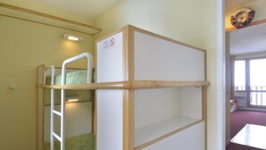 Un lit superposé avec une échelle, un tableau blanc et un panneau indiquant «Il est interdit de fumer».