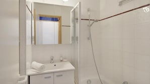 Une salle de bain moderne avec un lavabo blanc, un miroir et une douche.