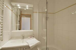 Ein modernes Badezimmer mit einer Duschkabine aus Glas, einem weißen Waschbecken und einem Spiegel darüber.