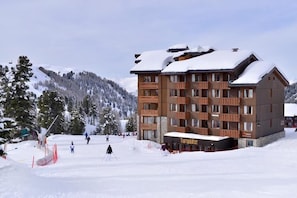 Un hotel de varios pisos con una pista de esquí al fondo.