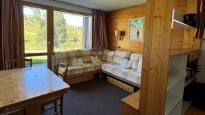 Un interior de cabaña acogedor con una mesa de comedor de madera, un sofá y una zona de cocina.