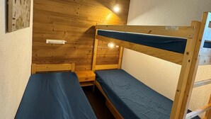 Dormitorio con literas, paredes de madera y una sola mesita de noche.