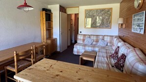 Une pièce chaleureuse avec une table à manger en bois, un canapé et une lampe rouge suspendue au plafond.