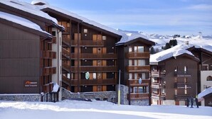 Un hôtel à plusieurs étages, doté de balcons en bois et d’une base en pierre.