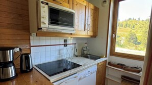 Une cuisine de taille réduite, dotée de meubles en bois, d’un four à micro-ondes, d’une cuisinière, d’un évier et d’un lave-vaisselle.