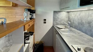 Una cucina compatta con mensole in legno, un piano cottura integrato e un lavello moderno.
