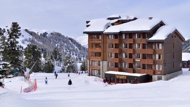 Un hotel a più piani con una pista da sci sullo sfondo.