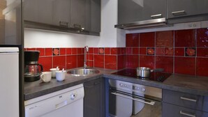 A modern kitchen with grey cabinets, a stainless steel sink, and red-tiled backsplash. - 100m from ski slopes, 3rd floor, view ski slopes, balcony, tv, 51m², La Plagne (La Plagne)