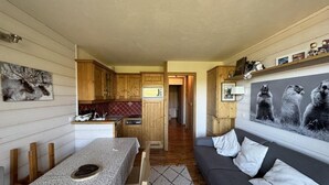 Un ambiente compatto con angolo cottura, zona pranzo e divano.