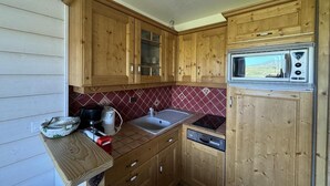 Una cucina compatta con mobili in legno, un forno a microonde, un lavandino e una lavastoviglie.