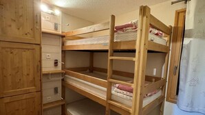 Camera con letto a castello in legno, un'armadi e una piccola unità a scaffali.