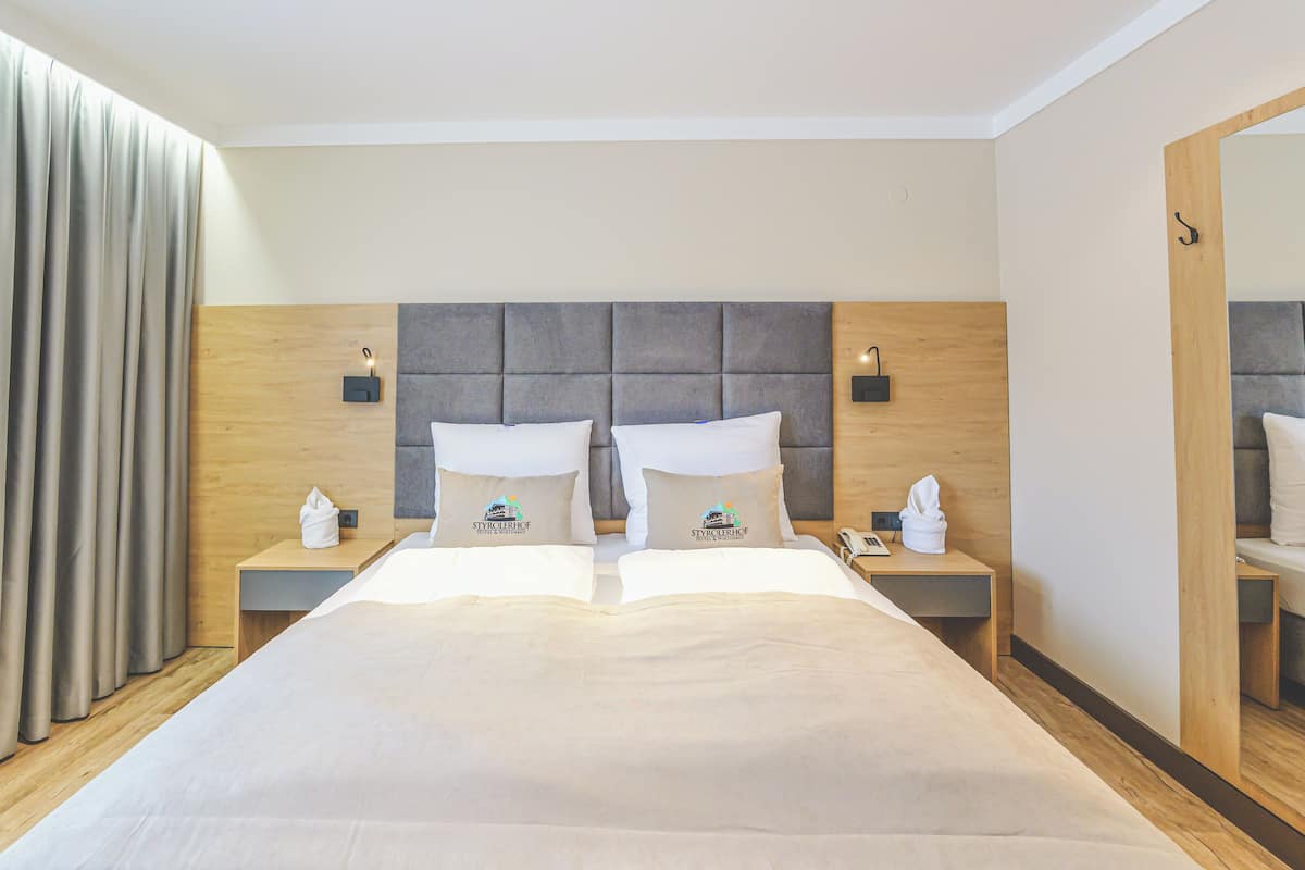 Hotellihuone, jossa on suuri sänky, kaksi yöpöytää, puinen sängynpääty ja peili seinällä.