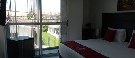 Habitación de hotel con una cama grande, televisión, escritorio y vistas al exterior.