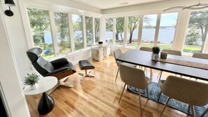 A modern dining area with a large table, chairs, and a view of a lake.
