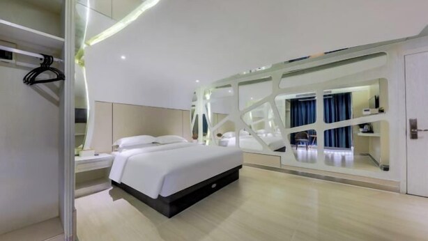 A modern hotel room with a large bed, a walk-in closet, and a mirrored wall. - Royal Hotel (Shenzhen)