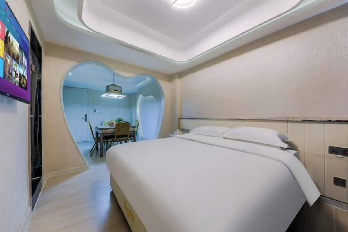 A modern hotel room with a bed, a desk, and a chair.
