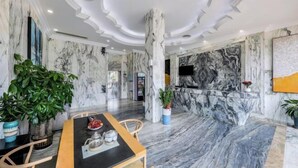 A modern interior with a marble floor, a dining table with chairs, and a large potted plant. - Royal Hotel (Shenzhen)