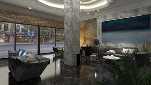 A lobby with a marble column, seating area, a large painting, and a view of the street. - Royal Hotel (Shenzhen)