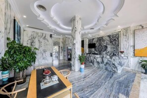 Un hall d’hôtel avec un sol en marbre, un espace salon central et une grande colonne.