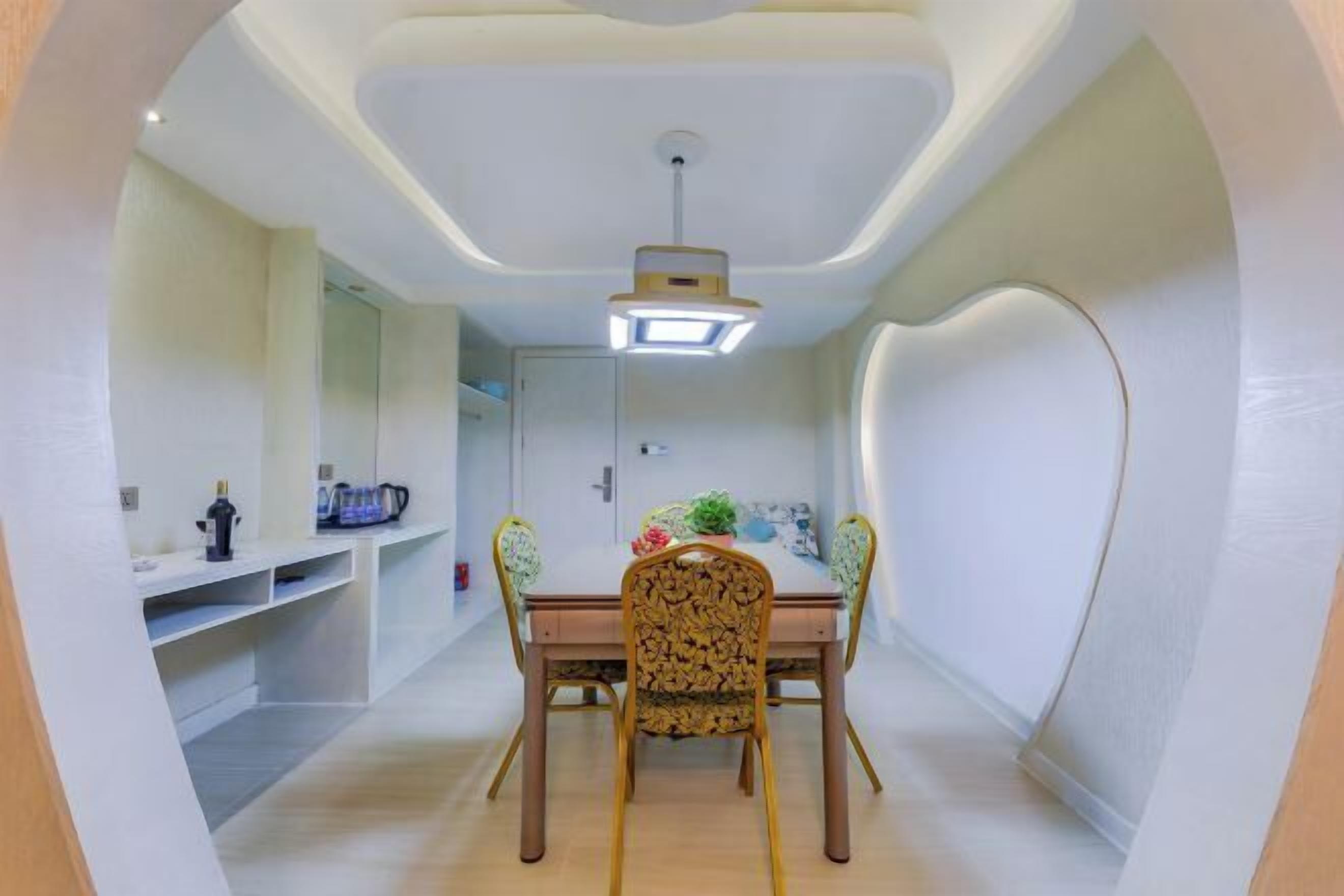 A dining area with a table, chairs, and a ceiling light fixture.