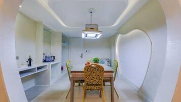 A dining area with a table, chairs, and a ceiling light fixture.