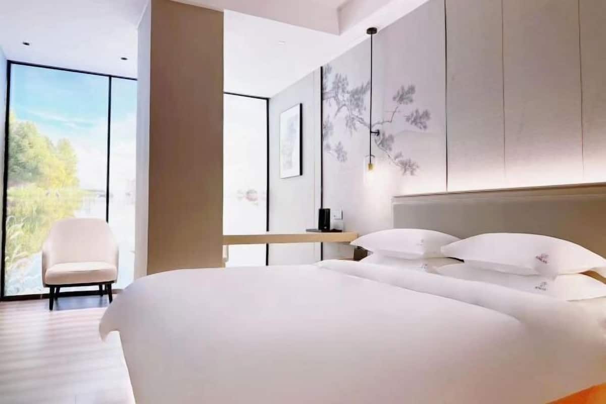 A modern bedroom with a large bed, a chair, and a desk.